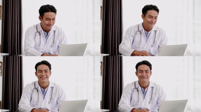 肖像年轻的亚洲医生在笔记本电脑上打字时微笑