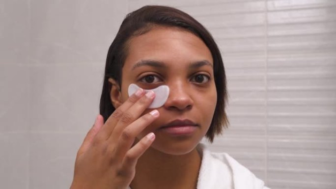 皮肤黝黑的女人使用眼罩来抵抗皱纹。皮肤水合作用。