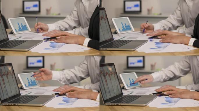 男人和女人使用笔记本电脑平板电脑查看带有图表的论文。市场营销策略分析，股票市场交易，企业团队合作。特