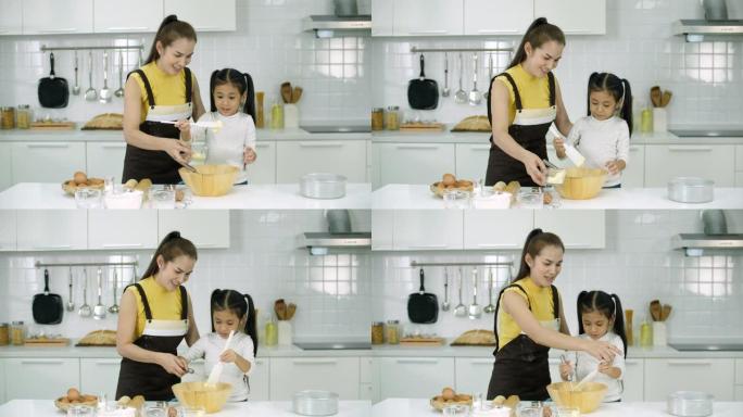 母亲和小女儿在厨房里为饼干或蛋糕做面团