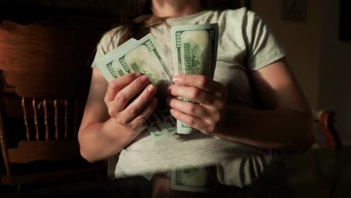 沮丧的孕妇持有最新的100美元的美国钞票，并检查美国现金金额。世界经济危机