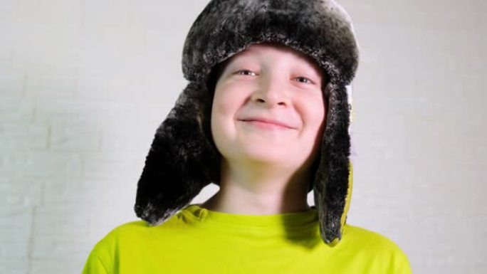 一个快乐微笑的白人男孩戴着带耳瓣的冬季保暖帽的肖像