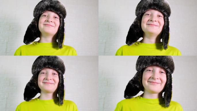 一个快乐微笑的白人男孩戴着带耳瓣的冬季保暖帽的肖像