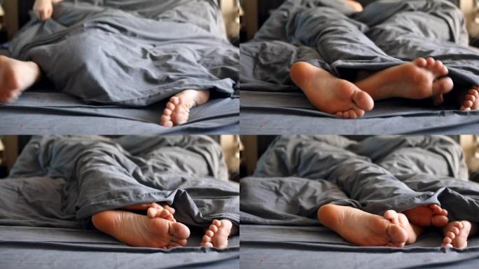 夫妻腿女人和男人在床上的灰色毯子下