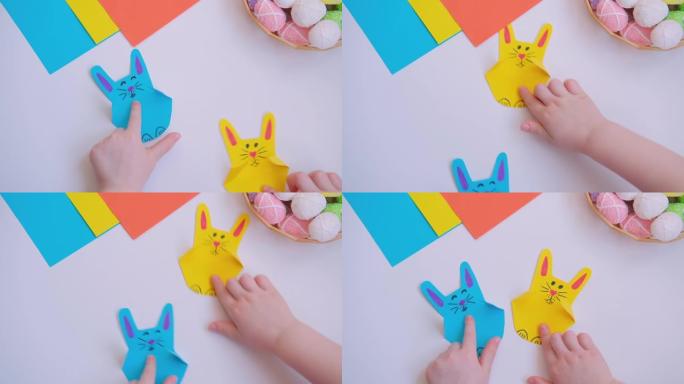 孩子们的手指拿着复活节工艺七彩纸兔子和跳跃。