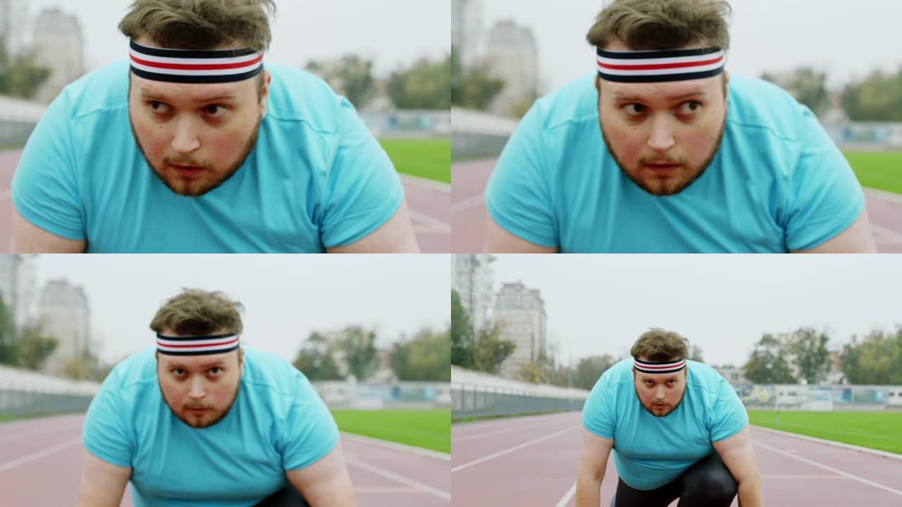集中的肥胖男子穿着运动服在体育场进行艰苦的锻炼，他站在镜头前的起跑线上。在阿里·阿列克谢迷你上拍摄