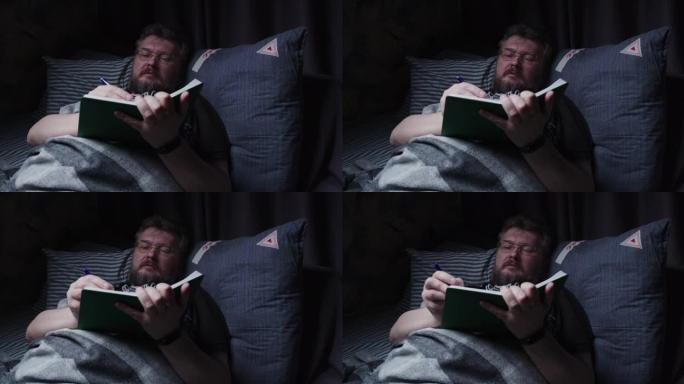 成熟的男人在睡觉前在床上做笔记