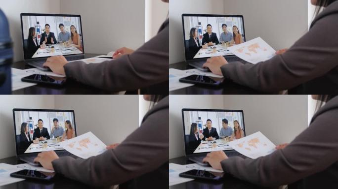 亚洲女商人视频会议通过笔记本电脑上的网络摄像头与团队在酒店房间举行。商务旅行概念