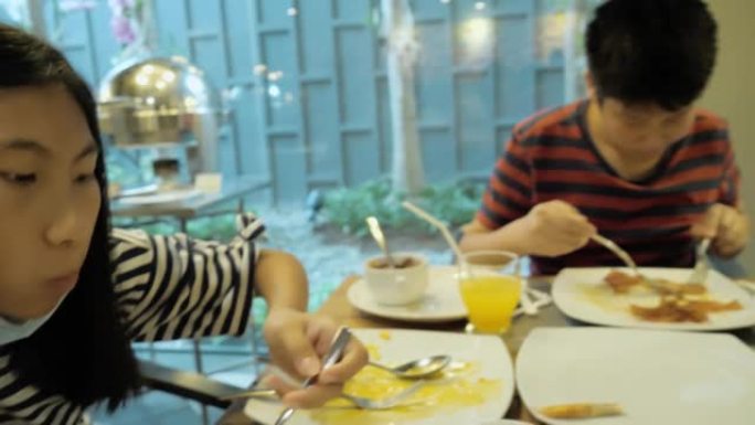 快乐的亚洲儿童在度假旅行期间在酒店自助餐厅附近享用早餐，生活方式理念。