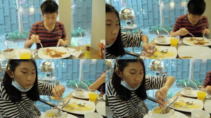 快乐的亚洲儿童在度假旅行期间在酒店自助餐厅附近享用早餐，生活方式理念。