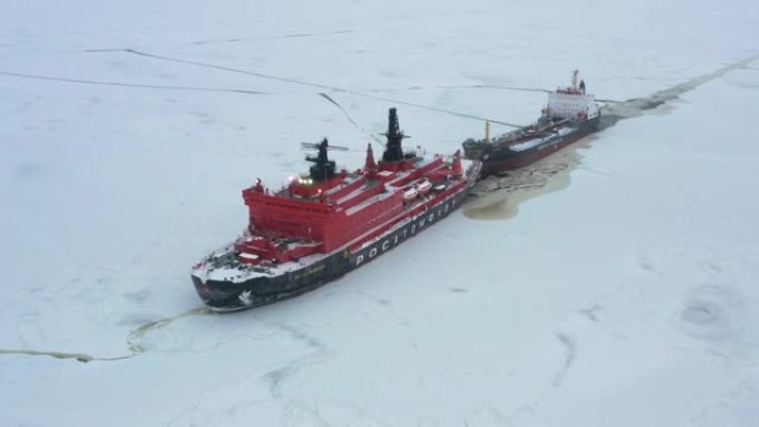 破冰船在冰上拖着一艘油轮。