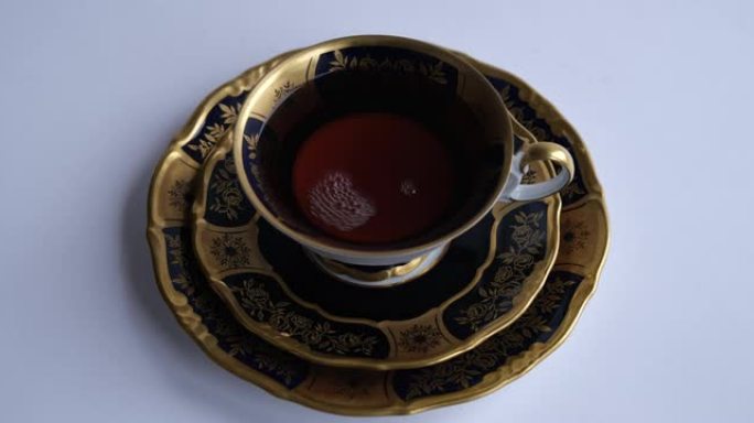 一杯茶。将浓茶从茶壶倒入镶有黄金的老式杯子中