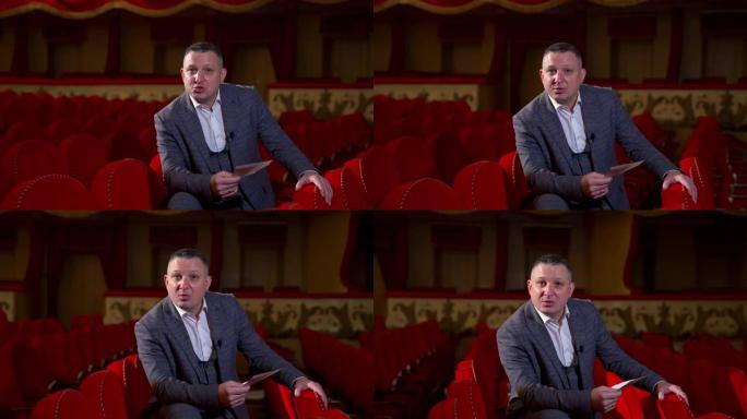主持人宣布未来的剧院季节。演员坐在红色天鹅绒椅子上的空剧院里。红色经典剧院室内。