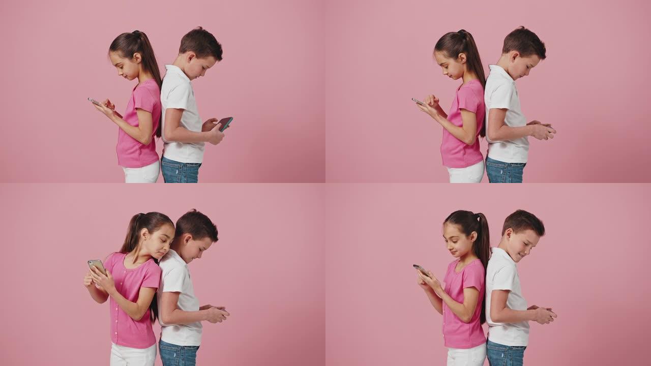 小男孩和女孩背靠背站在智能手机上，好奇的妹妹偷看兄弟手机