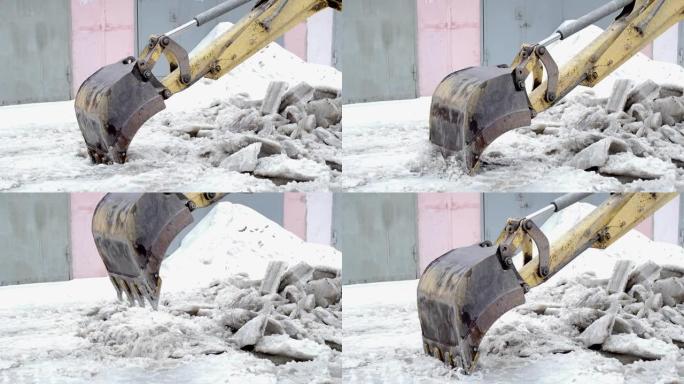 拖拉机铲斗打破了压缩的冰雪。除雪特写。慢动作。