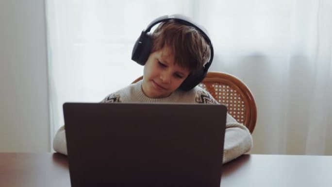 高加索孩子在家与老师一起使用视频会议进行视频通话。男孩戴着耳机在家在线学习看网络课。教育在线概念