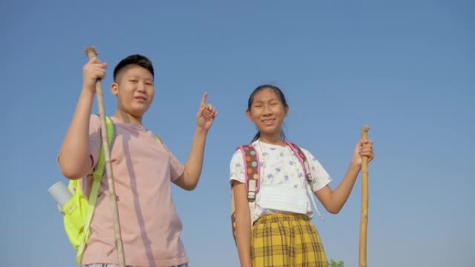 快乐的亚洲背包客孩子们在早晨的蓝天下举手，生活方式的概念。