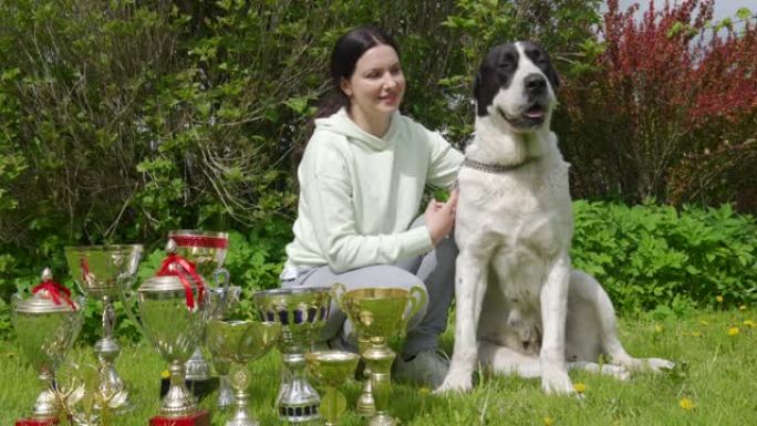 女宠物主人和她的获胜者中亚牧羊犬与狗一起颁奖，女子与阿拉巴伊在获胜杯附近