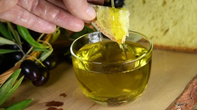 一只手将面包浸入冷榨橄榄油中
