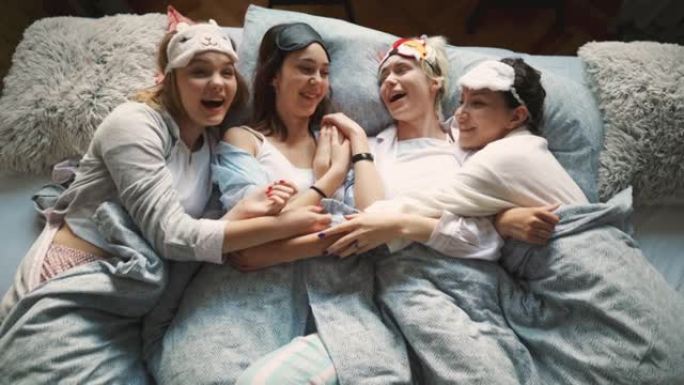 穿着睡衣的四个女友躺在床上，拥抱和交谈
