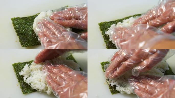 戴着手套的厨师正在烹饪寿司。寿司由米饭、紫菜、黄瓜、奶油奶酪制成。开胃营养食品概念。