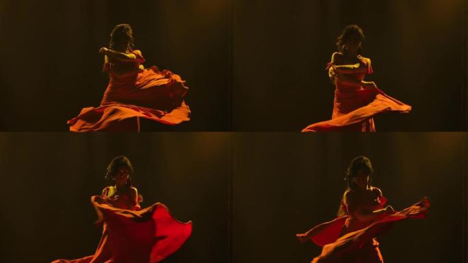 穿着红色长裙的黑发女人在黑暗烟熏工作室的黄色霓虹灯背景下跳舞热情的弗拉门戈舞。特写阿根廷女舞者旋转跳