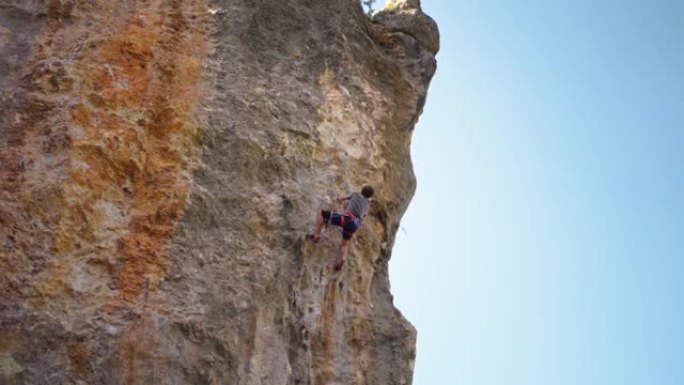 强壮而熟练的男子登山者通过艰难的路线在石灰墙悬崖上攀登，进行了几次艰苦的努力和夹子绳索