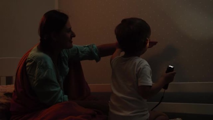 4k视频，年轻的母亲在晚上睡觉前与她的小儿子在阴影剧院或木偶戏中玩耍