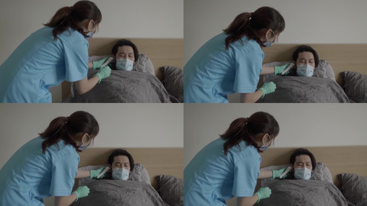 亚洲医务人员为病人量体温，而病人躺在家里的床上