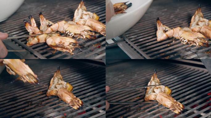 大型烤虾的特写。厨师的手把海鲜从烤架上拿下来，放在盘子里。