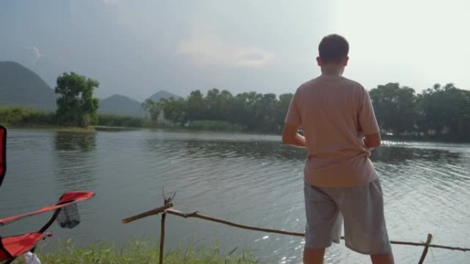 快乐的亚洲男孩在湖边钓鱼，与家庭户外露营，生活方式理念。