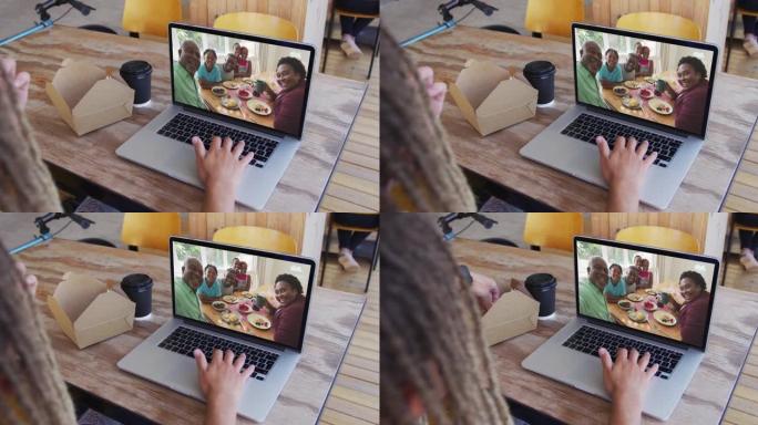 混合种族男子坐在咖啡馆里，用笔记本电脑与家人进行视频通话