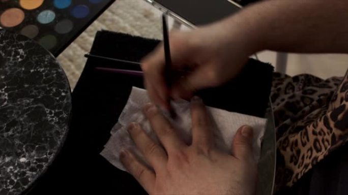 一名男性化妆师用纸巾从刷子上清洗眼影的4k视频片段