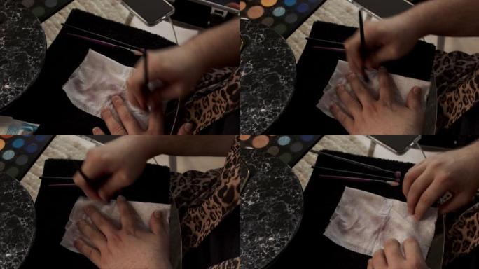 一名男性化妆师用纸巾从刷子上清洗眼影的4k视频片段