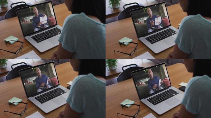 混血女商人坐在办公桌前，用笔记本电脑与男同事进行视频通话