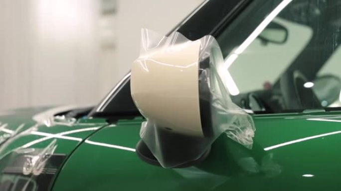 绿色背景上的汽车后视镜。油漆上的贴纸乙烯基薄膜。