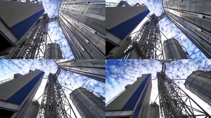 现代工业厂房上的金属建筑。美丽天空背景上的大型谷物升降机。从下面看。