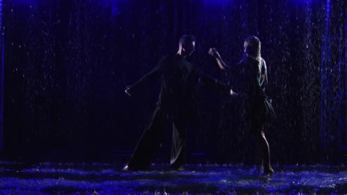 舞厅舞者在倾盆大雨中跳舞热情的拉丁美洲bachata舞蹈。一对年轻夫妇的剪影，穿着湿衣服，黑色工作室