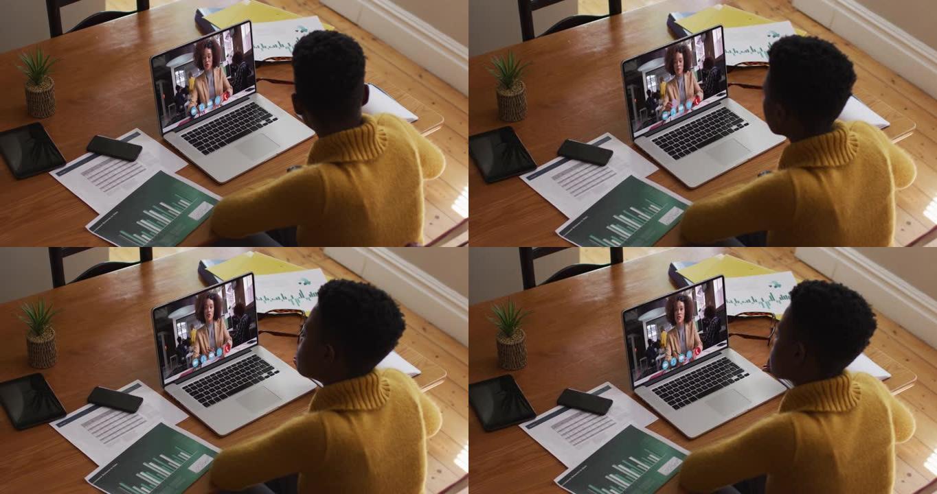 非裔美国女商人坐在办公桌前，用笔记本电脑与同事进行视频通话