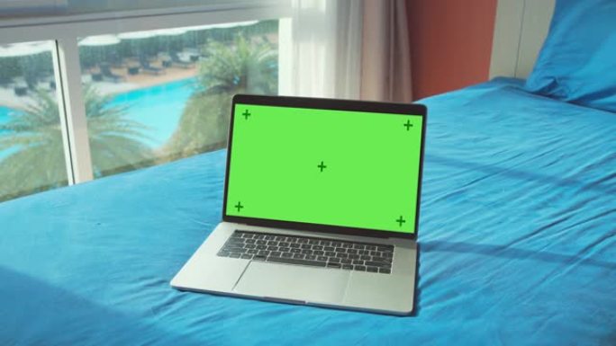 家庭内部床上绿屏显示的笔记本电脑。