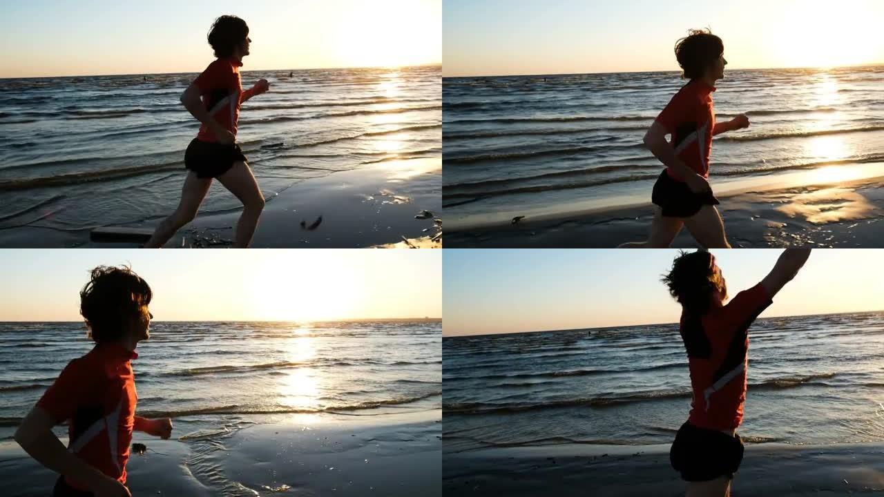 人奔向大海，在日落时风筝冲浪者的背景下，对终点感到高兴