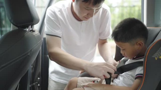 亚洲父亲在旅行中点击孩子进入汽车座椅，父亲全天与孩子互动。