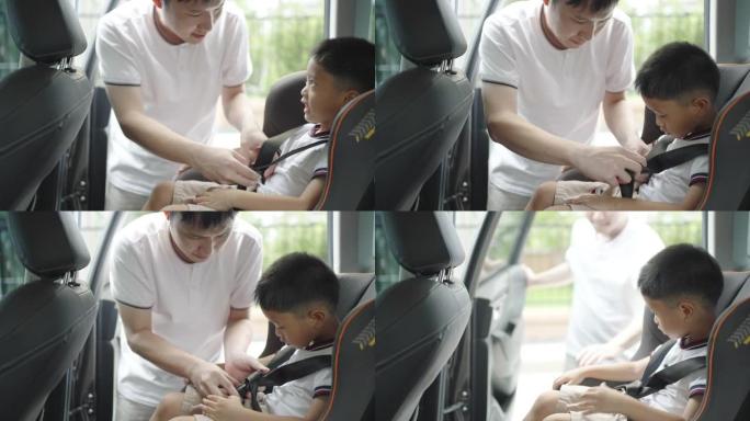 亚洲父亲在旅行中点击孩子进入汽车座椅，父亲全天与孩子互动。