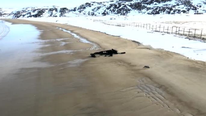 在下雪的冬季，在海边淹死的旧失事渔船的空中俯视图。镜头。俄罗斯特里伯卡雪沙海岸附近冷水中被毁船的鸟瞰