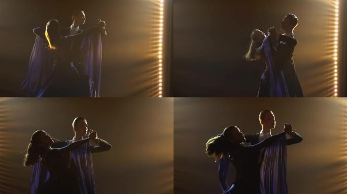 由专业舞厅舞者表演的古典华尔兹。剪影年轻男女练习舞步，在黑暗的工作室里用烟雾和聚光灯在地板上表演。特