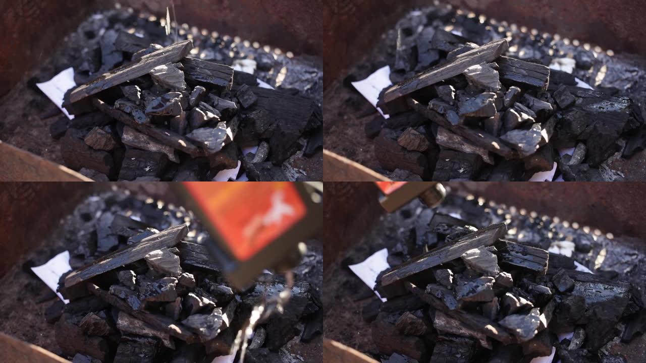 一个人用纸火柴和煤点燃火。金属烤架。在大自然中休息，烹饪烧烤的露台篝火是一种点火手段