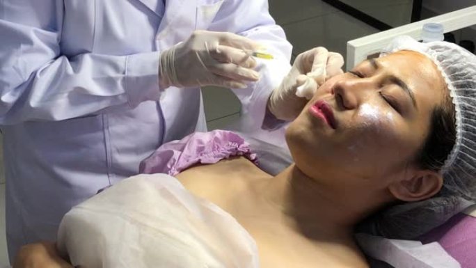 在面部美容院接受面部注射治疗的亚洲中国女性顾客