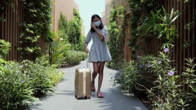 快乐的亚洲女孩和行李在阳光明媚的日子与家人一起度假旅行期间入住/退房后步行到酒店的房间，生活方式理念