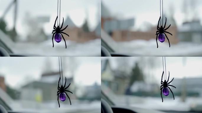 在高速公路上行驶时，一个蜘蛛玩具悬挂在汽车的仪表板上。特写镜头