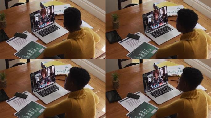 非裔美国女教师在家里用笔记本电脑进行视频通话时说话和做笔记
